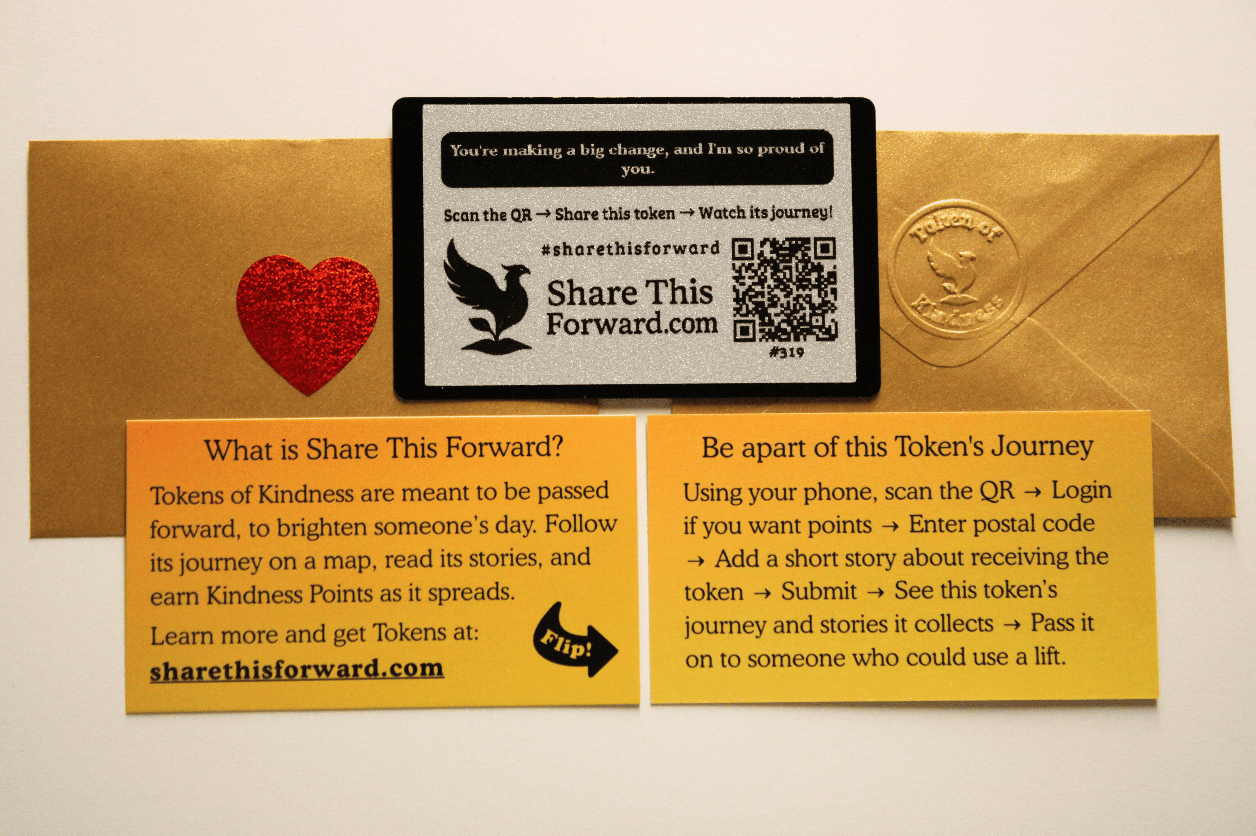 A Share This Forward Kindness Note shown with its gold envelope, heart sticker, and instruction cards. The QR card invites people to scan it, follow its journey, and pass it forward to spread kindness.
