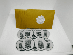 Set of 10 Share This Forward Kindness Tokens with uplifting affirmations and QR codes for tracking their journey, displayed with elegant golden envelopes sealed with silver heart stickers — a simple way to inspire kindness and connection