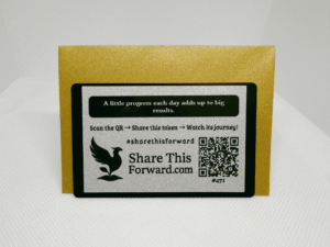 Single Share This Forward Kindness Note paired with a gold shimmer envelope sealed with a silver heart emblem, featuring the quote “A little progress each day adds up to big results” and a QR code to track its kindness journey online