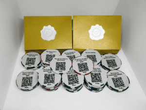Collection of 50 Share This Forward Kindness Tokens with positive messages and QR codes, displayed with matching golden envelopes sealed with silver heart stickers — perfect for sharing kindness and tracking each token’s journey online